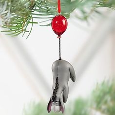 an ornament hanging from a christmas tree with a hand holding a bell on it