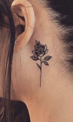 a woman's ear with a small rose tattoo on it