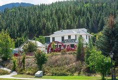 a large white building sitting on the side of a lush green forest covered hillside next to trees