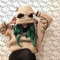 a woman with green hair is wearing a knitted hat and sitting on the floor