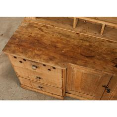 an old wooden desk with holes in the top and drawers on one side, next to a concrete floor