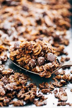 a spoon filled with chocolate granola on top of a table