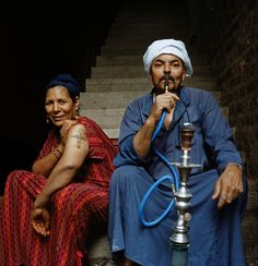 two people are sitting on the steps and one is holding a pipe in his mouth