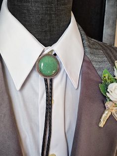 Custom Green Aventurine Bolo Tie with a Silver, Gold or Copper Round Metal Setting.  You pick setting and end cap color and either genuine leather bolo cord or vegan bolo cord and color.  I will hand select a stunning High Quality Green Aventurine Stone.  These stones are amazing since they look a lot like Jade!  No need for photos of stones since they all look similar.  The Bolo Setting in this listing are made in the USA and have a Tension Clasp that is leather cord friendly!  High Quality Genuine Green Aventurine Gemstones available.  Let your creatively run free and create a Bolo Tie that is exactly how you want it to be!    We also have other styles of Black Onyx Bolo Ties so check our listings.  We also create Artisan one of a kind Silversmith Bolo Ties in Recycled Sterling Silver, C Mens Bolo Tie Wedding Outfit, Bolo Tie Wedding, Western Bolo Tie, Green Aventurine Stone, Groom Ties, Aventurine Stone