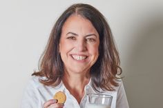 a woman holding a glass of milk and a cookie