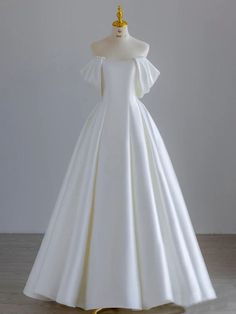 a white wedding dress on display with a gold ring in it's centerpiece