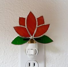 a light switch with a red and green flower on it's cover in the shape of a leaf