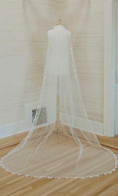 a white wedding veil on top of a mannequin in the corner of a room