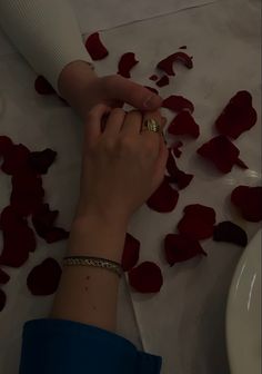 a woman's hand on the ground with rose petals around her and a white toilet in the background