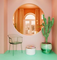 there is a mirror on the wall next to a chair and a potted cactus