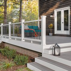 a deck with white railings and blue couch on the back porch next to trees