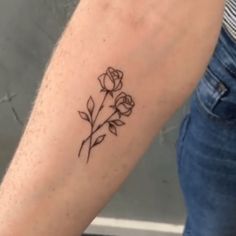 a person with a tattoo on their arm that has three roses in the middle and two leaves at the bottom