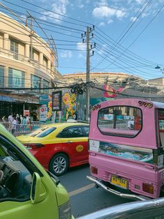 a pink bus driving down a busy street next to parked cars and people walking on the sidewalk