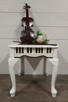 a white piano with a violin on top and flowers sitting on it's side