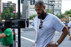 a man with headphones standing next to a camera on a pole in the street