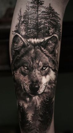 a man's leg with a wolf tattoo on it and trees in the background