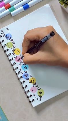 a person is drawing flowers on a notebook