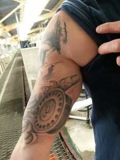 a man with a clock tattoo on his arm is holding something in his right hand