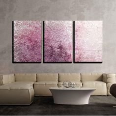 three paintings on the wall in a living room, one is pink and the other is white