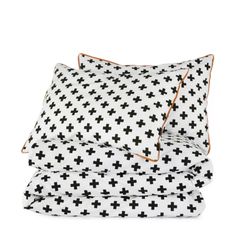 the black and white bedding is neatly made with cross print on it, along with an orange piping