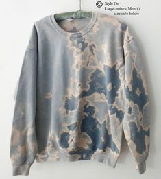 a blue and white tie dye sweatshirt hanging on a hanger in front of a wall