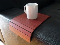 a white coffee cup sitting on top of a wooden table next to a black couch