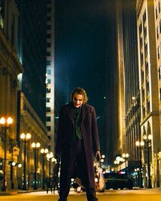 a man in a suit and tie standing on the side of a street at night