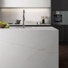 a modern kitchen with marble counter tops and black cabinets, along with green apples on the counter