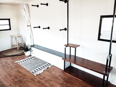 a living room with wooden floors and shelves on the wall, next to a potted plant