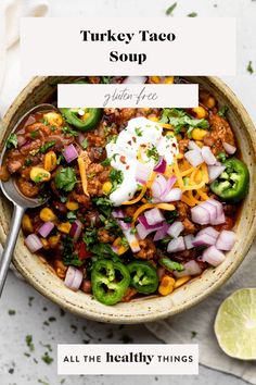 turkey taco soup in a bowl with a spoon and limes on the side