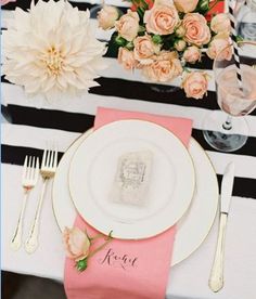 the table is set with pink and white flowers, silverware, and napkins