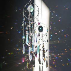 a wind chime hanging from the side of a white pillar with beads and crystals