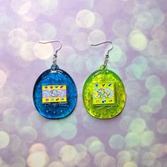 If you love Tamagotchis then you're gonna love these earrings! They're slightly transparent with glitter for that iconic Y2K look. They are kind of heavy, so just a heads up! Your earrings will arrive wrapped in tissue paper and in a clear cello bag. Try not to get them wet as the image is a sticker, if you get anything on them give them a gentle wipe.This listing is for a mismatch pair, if you want a matching pair be sure to check out the other listing over here!https://www.etsy.com/uk/listing/ Queer Clothes, Iconic Y2k, Weird Jewelry, Quirky Jewelry, Quirky Gifts, Heads Up, Green Glitter, Green Item, Retro Toys