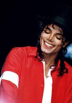 michael jackson smiling while wearing a red jacket and black hat