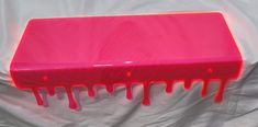 a pink table with red drips on it sitting on a white sheeted surface