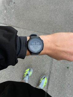 a person with a watch on their wrist is looking down at the ground while wearing running shoes