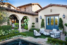 an outdoor patio with chairs and potted plants next to a pool in front of a house