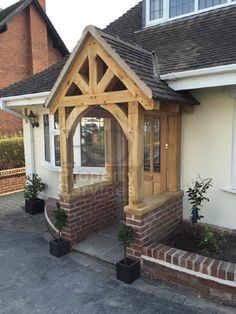 a house with a wooden front door and windows on the side of it, surrounded by brick planters