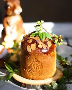 a cake with nuts and leaves on it sitting on top of a wooden plate next to an animal figurine