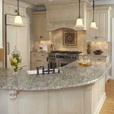 a large kitchen with marble counter tops and white cabinets, along with an island in the middle