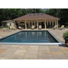 an empty pool with chairs around it and a house in the back ground behind it