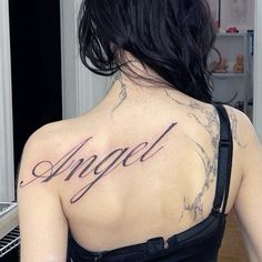 the back of a woman's neck with an angel tattoo