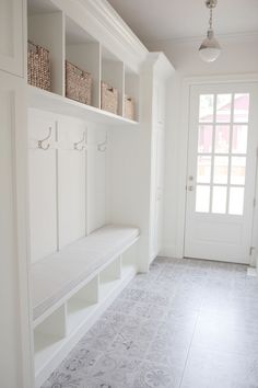 a white entryway with benches and baskets on the wall next to it's doors