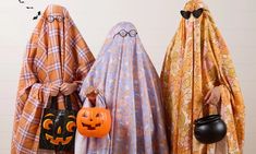 three people dressed up in costumes and holding pumpkins