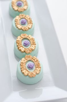 three cookies with gold and purple designs on them sitting on a white plate next to each other