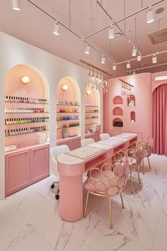 the interior of a nail salon with pink walls and marble counter tops, gold chairs and chandeliers