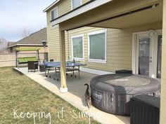 a cat is standing in the yard next to an above ground hot tub and table