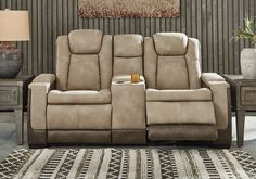 the reclining loveseat is in front of a table with a lamp on it