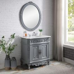 a bathroom vanity with a round mirror above it and two vases on the floor