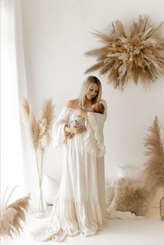 a woman holding a baby while standing in front of a star shaped object with feathers on it